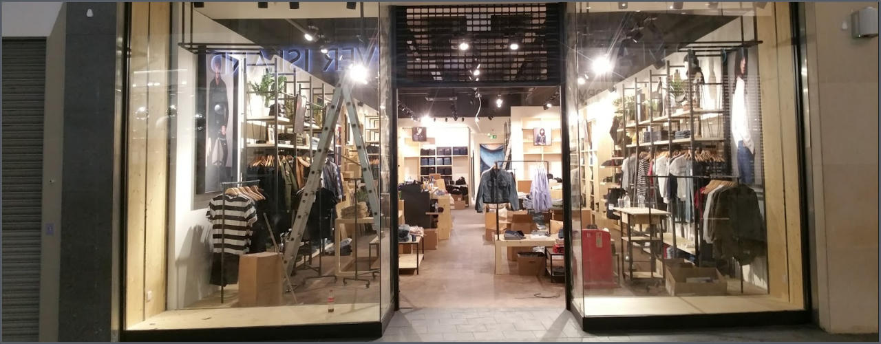 Completed retail interior with illuminated shelving, clothing displays and an open shop entrance